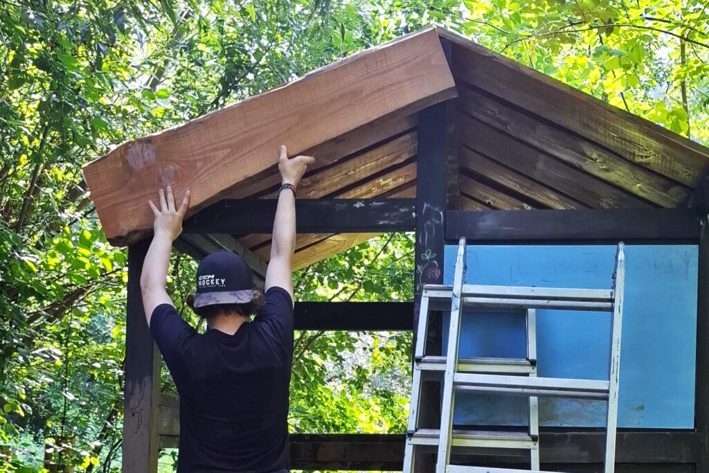 Freiwilliger bringt ein Brett an einem Unterstand an